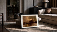 Moonlit winter church landscape print in a slim black frame leaning on a travertine coffee table