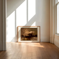 Moonlit winter church landscape print in an oak frame on a sunlit wood floor beneath tall window light