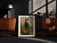 Black-framed Victorian woman holding flower basket print on a moody console with designer coffee-table books