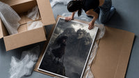 Long-haired warrior with armor on cliff framed print being unpacked from protective bubble wrap and a box