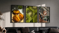 Mango, Kiwi and Coffee Set of 3 in black frames on a grey wall above a leather sofa