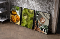 Mango, Kiwi and Coffee Set of 3 as black-framed prints leaning against a raw-plaster wall