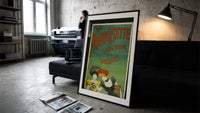Two elegant women tasting liqueur print in a slim black frame leaning on a dark sofa in a concrete print studio