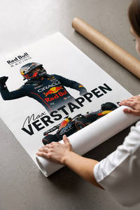 Hands unrolling a Verstappen victory print on concrete, revealing the celebrating driver and F1 car