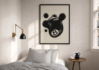 Melting 8 Ball print in a black frame above a bed with striped linens, a brass wall lamp and a sunlit window