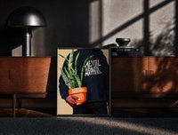 Black-framed Mental Health Matters Hoodie and Potted Plant print on the floor in front of a dark wooden console