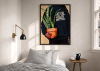 Mental Health Matters Hoodie and Potted Plant print in a black frame above a bed with striped linens