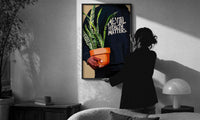 Mental Health Matters Hoodie and Potted Plant print in a slim black frame being hung on a sunlit wall in a monochrome room