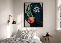 Mental Health Matters Potted Plant print in a black frame above a bed with striped linens