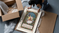 Snow-covered cottage in winter framed print being unpacked from protective bubble wrap and a box