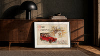 Vintage red touring car in snow print in a black frame leaning against a walnut console in lamplight