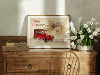 Vintage red touring car in snow print in an oak frame on a farmhouse dresser beside white tulips