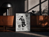 Black-framed Michael Jordan slam dunk print on a moody console with designer coffee-table books