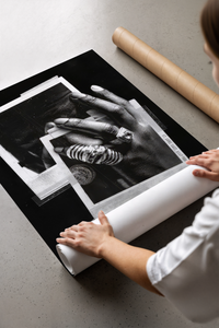 Hands unrolling the black and white Michael Jordan six rings basketball poster on a concrete floor
