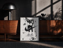 Black-framed KAWS figure wearing Air Jordan sneakers print on a moody console with designer coffee-table books