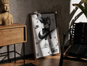 Walnut-framed KAWS figure wearing Air Jordan sneakers print leaning against a sunlit rustic brick wall