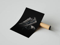 Mocha-toned sneaker at a three-quarter angle on glossy black, unrolled from a kraft shipping tube