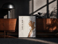 Black-framed White-haired smiling anime man profile print on a moody console with designer coffee-table books