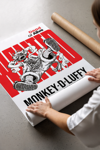 Hands unrolling the Luffy wanted art print on a grey concrete surface