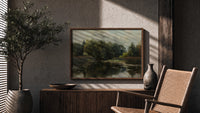 Tranquil pond with lily pads print in a wood frame above a fluted sideboard beside an olive tree