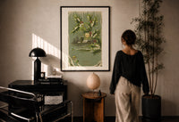 Church A Merry Christmas print in a black frame on a sunlit plaster wall, a person looking on beside a mushroom lamp