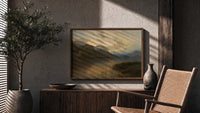 Mountain lake at sunset print in a wood frame above a fluted sideboard beside an olive tree