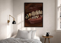Mouth with Jeweled Gold Grillz print in a black frame above a bed with striped linens, a brass wall lamp and a sunlit window