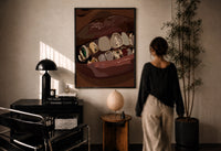 Mouth with Jeweled Gold Grillz print in a black frame on a sunlit plaster wall, a woman looking on beside a mushroom lamp