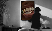 Mouth with Jeweled Gold Grillz print in a slim black frame being hung on a sunlit wall in a monochrome room