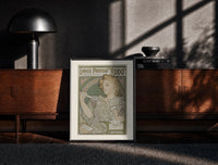 Black-framed Art Nouveau woman spraying perfume print on a moody console with designer coffee-table books