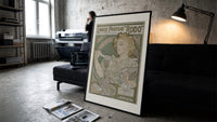 Art Nouveau woman spraying perfume print in a slim black frame leaning on a dark sofa in a concrete print studio