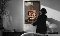 My Cup Runneth Over Coffee print in a slim black frame being hung on a sunlit wall in a monochrome room
