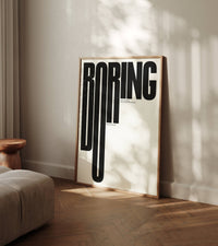 Never Be Boring bold black cream typography wall art leaning against wall in modern living room