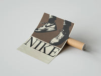 Gently curled Nike Air Force 1 Low on Brown print beside its protective shipping tube