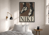 Nike Air Force 1 Low on Brown print in a black frame above a bed with striped linens, a brass wall lamp and a sunlit window