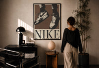 Nike Air Force 1 Low on Brown print in a black frame on a sunlit plaster wall, a person looking on beside a mushroom lamp