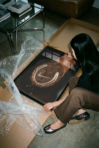Woman kneeling on concrete unpacking the Nike hoof swoosh print from a box amid bubble wrap