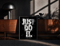 Black-framed Just Do It typography design print on a moody console with designer coffee-table books