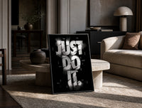 Just Do It typography design print in a black frame leaning on a travertine table in a sunlit lounge