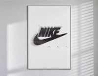 Blurred Nike swoosh logo poster in a slim frame on a bright wall with soft window light