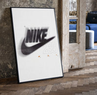 Blurred Nike swoosh logo print in a black frame leaning beside a vintage door on parquet