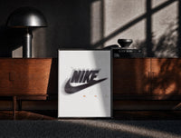 Black-framed Blurred Nike swoosh logo print on a moody console with designer coffee-table books