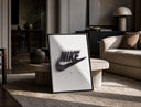 Blurred Nike swoosh logo print in a black frame leaning on a travertine table in a sunlit lounge