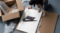 Blurred Nike swoosh logo framed print being unpacked from protective bubble wrap and a box