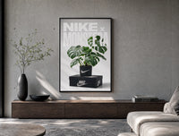 Monstera plant in Nike pot poster framed above a wood console in a concrete-wall living room