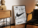 Brass-framed Nike Swoosh logo design study print leaning in a warm styled corner by a sculpture