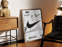 Brass-framed Nike Swoosh logo design study print leaning in a warm styled corner by a sculpture