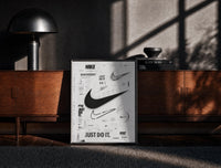 Black-framed Nike Swoosh logo design study print on a moody console with designer coffee-table books