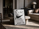 Nike Swoosh logo design study print in a black frame leaning on a travertine table in a sunlit lounge