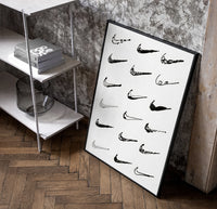 Various hand-drawn Nike swoosh logos poster in a black frame leaning beside a shelf in a raw-plaster loft
